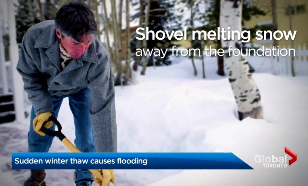 A man shovels snow away from the foundation of a house during a sudden winter thaw to prevent water damage, as seen on a news report from Global Toronto, with a snowy backdrop and a caption